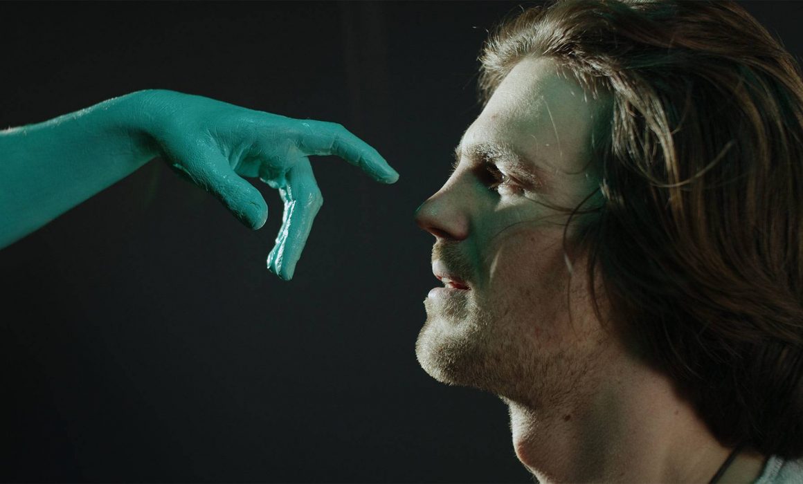 Thumbnail of the spot "Art May Touch / Kunst darf berühren": A hand covered in green paint almost touches the nose of a man.