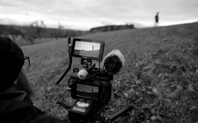 Black and White image of Imanuel filming a scene on a field for his shortfilm