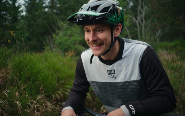 Stevie Schneider is trying to scare off a mountain cock that is blocking his way while biking.