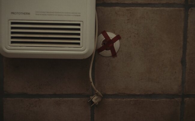 An outlet on a wall is taped so nobody will use it.