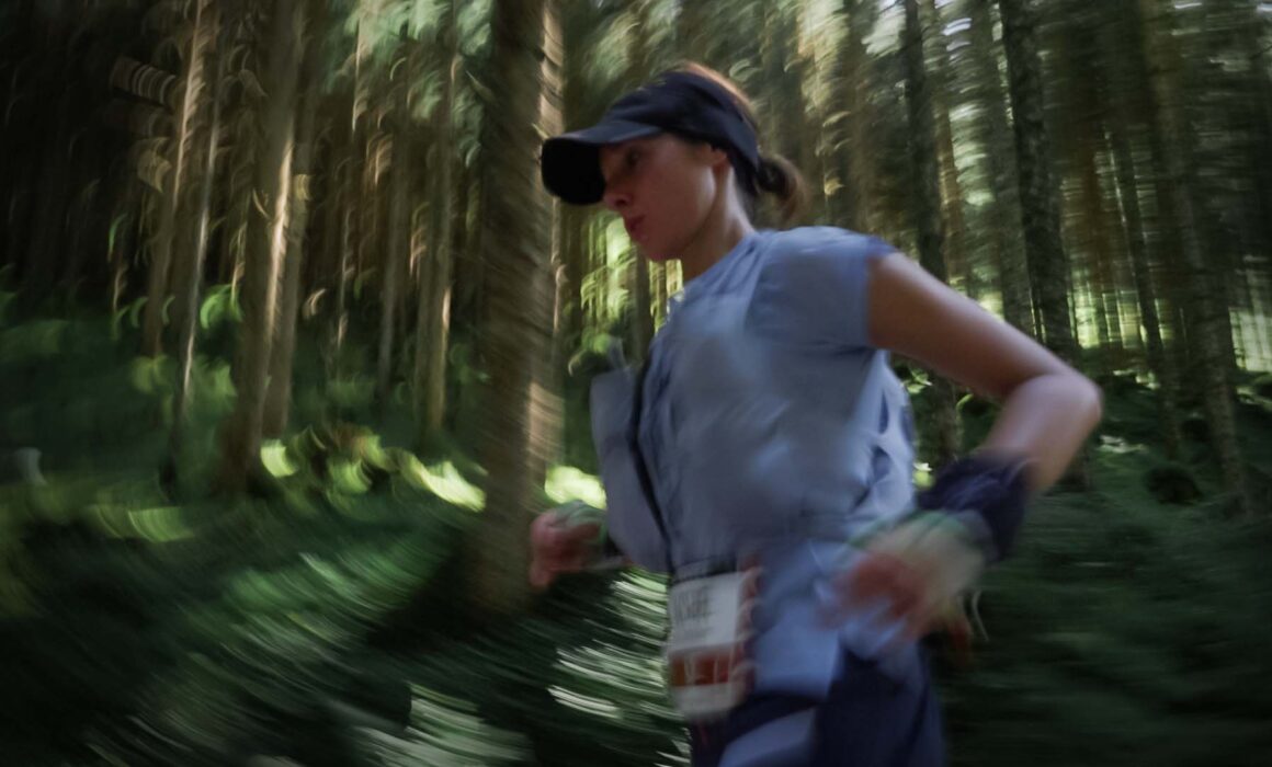 A blurry image of a runner inside a forest.