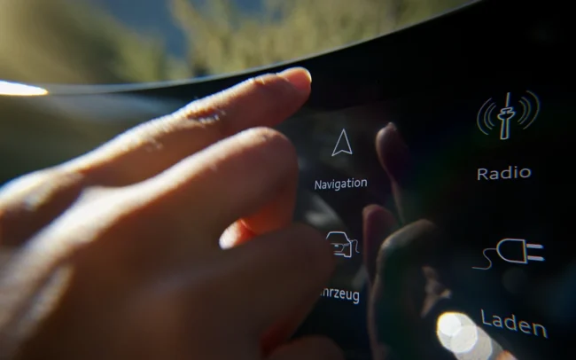 Extreme close up of a finger pressing the Navigation button on the display of an AUDI Q6 e-tron.
