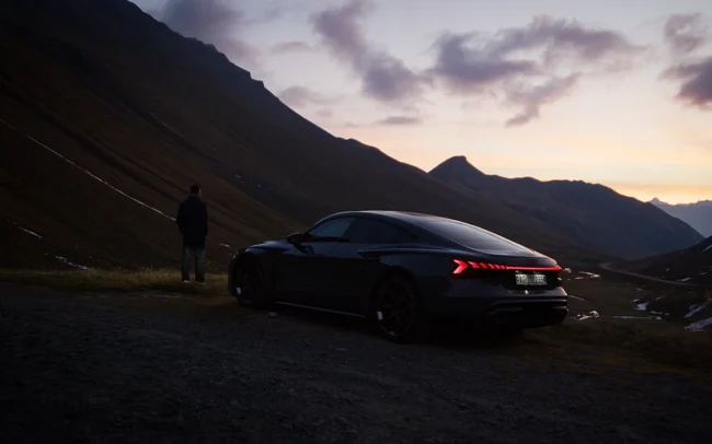 A man standing next to his AUDI RS e-tron GT overlooking the Swiss Alps.