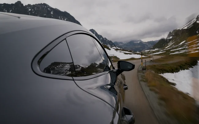 Reflections of mountains on an AUDI RS e-tron GT driving through the Swiss Alps. Camera hard mounted to the outside of the car.