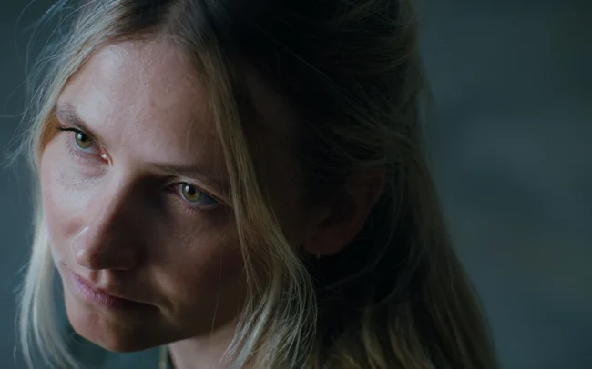 A close up of Elisa Deutschmann's face in dramatic lighting.