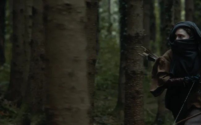 A hunter with a turban and bow chasing after the witch in a forest.