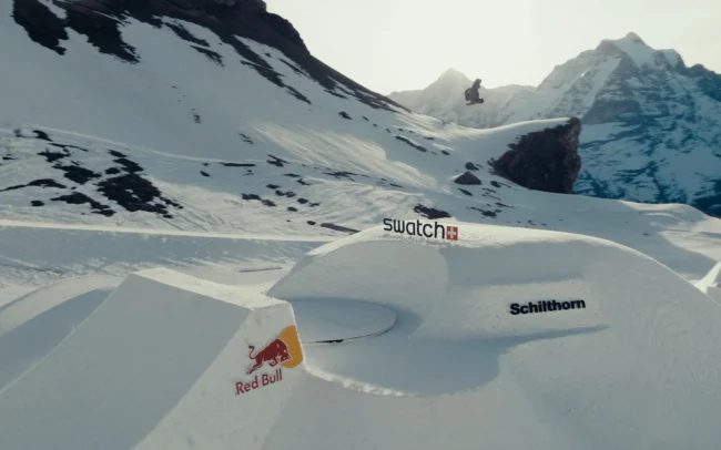 Professional snowboarder mid-air above giant jump