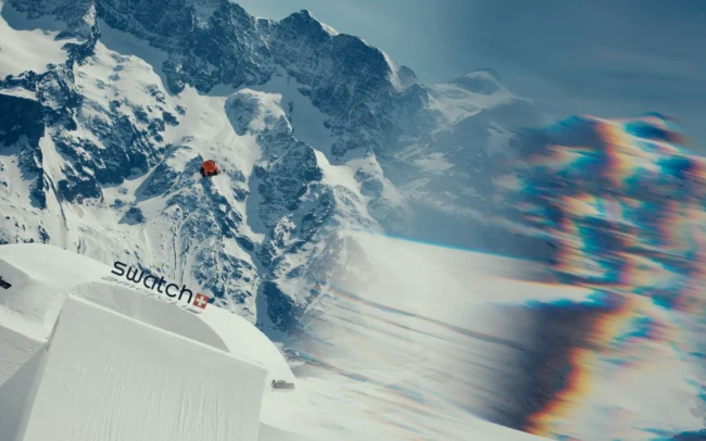 A snowboarder going over a huge kicker. Beautiful refractions on the side of the frame.