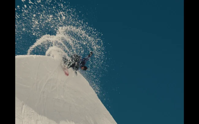A snowboarder carving with slushy snow flying all over.