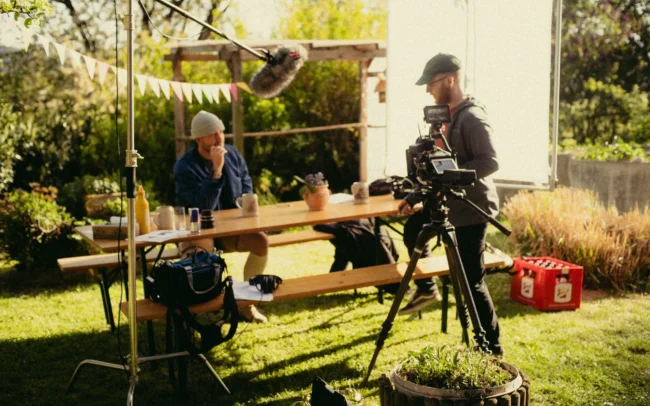 Behind-the-scenes production photo showing the camera crew setting up a shot with a professional cinema camera rig on location for the Austrian Kiwi short film.