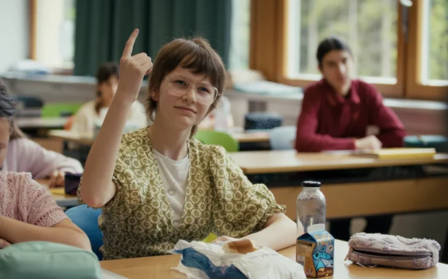 A close-up reaction shot of a student looking visibly confused by the teacher's incorrect English pronunciation.