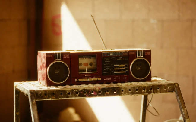 Retro red boombox radio resting on a metal stepladder on a warm-toned construction site film set from Holy Moly films.